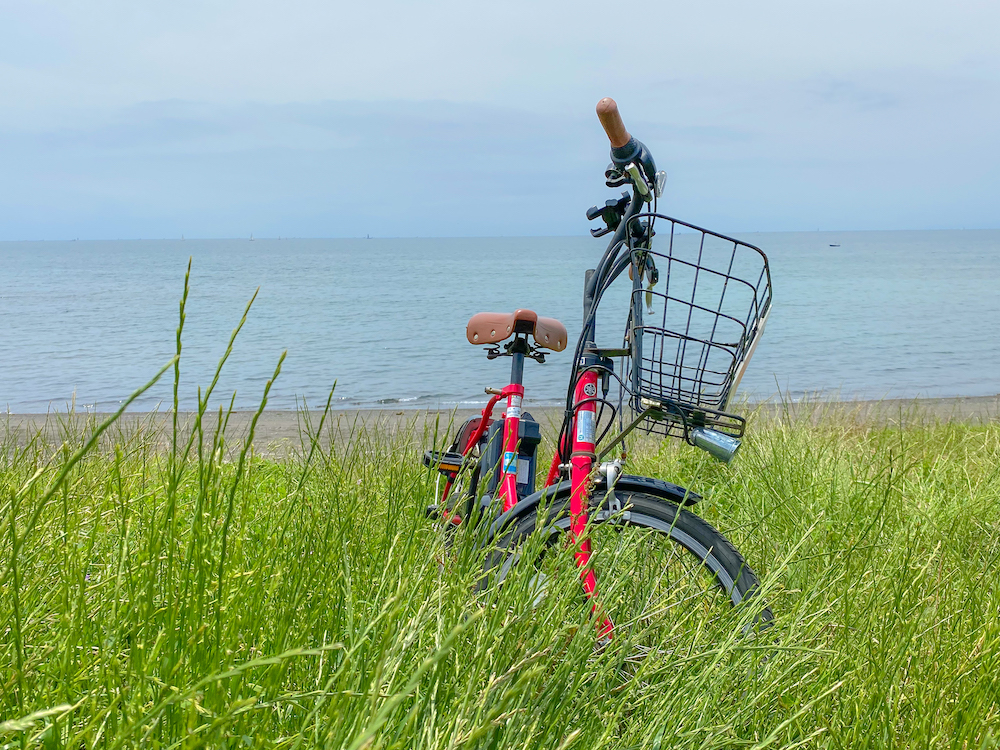三戸浜の海辺の草むらに止めた赤い自転車。2022年6月5日.撮影：SHUN RocketDive
